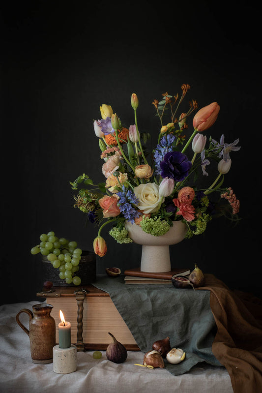 Stilleven | Pastel kleurig bloemstuk met bijbel, vijgen, bloembollen en druiven